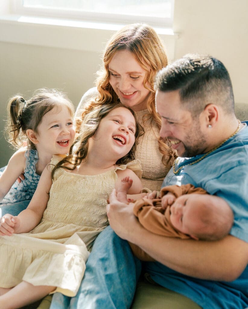 Family of 5 in Portland Oregon snuggled on a couch with their newborn baby